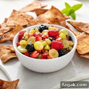 White bowl of fruit salsa with cinnamon chips in the background.