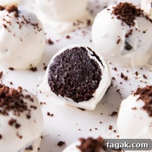 This Oreo Balls recipe is easy, sliced in half to show the cake ball center packed with Oreo cookies on a sheet with more Oreo cream cheese truffles