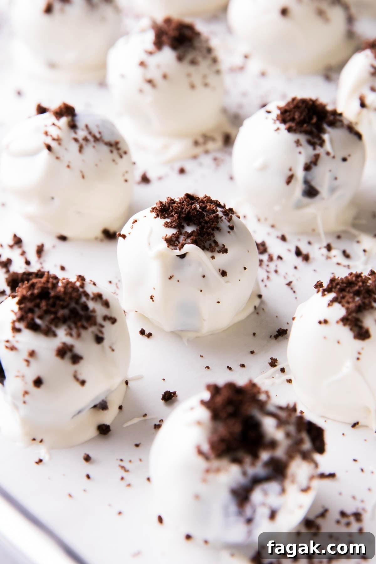 3 Ingredient Oreo truffles on a lined sheet packed with cream cheese, coated in white chocolate, and topped with Oreos for a no bake oreo truffles recipe.