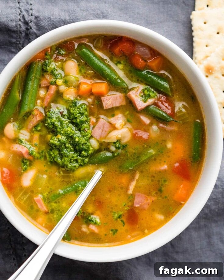 A bowl of ham barley soup with vegetables and pistou.