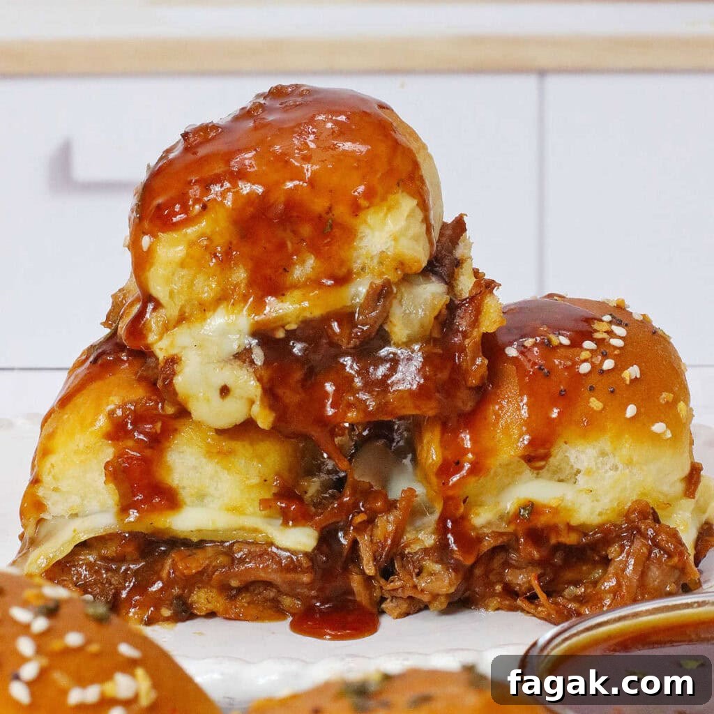BBQ Brisket Sliders Made from Leftover Beef Brisket 2 A stack of three beef brisket sliders with cheese and barbecue sauce on a white plate.