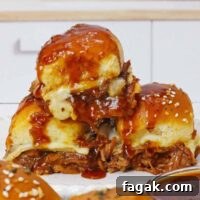 BBQ Brisket Sliders Made from Leftover Beef Brisket 12 A stack of three beef brisket sliders with cheese and barbecue sauce on a white plate.