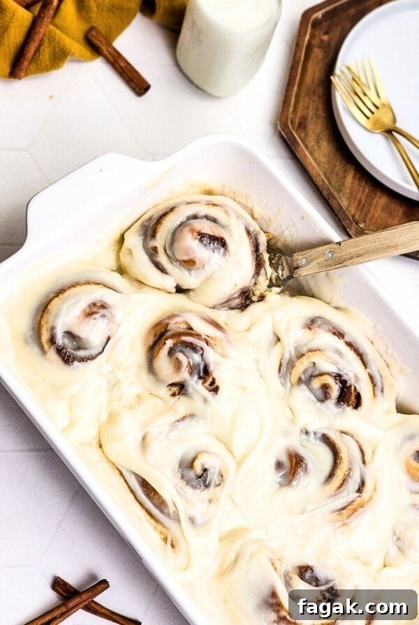 Gooey rolls in a white baking dish with frosting on top.