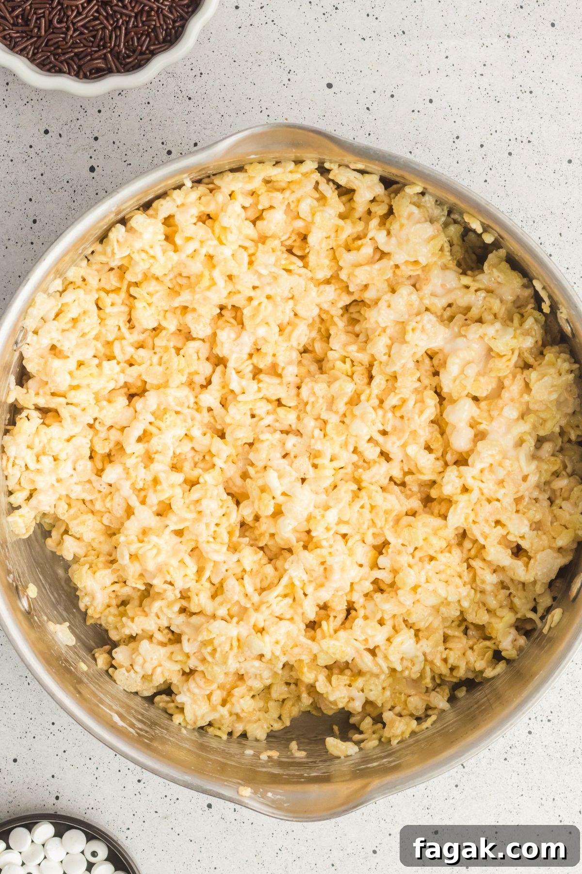 Rice krispie cereal mixed with melted butter and marshmallows in a large saucepan.