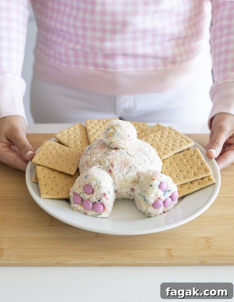Easter dessert shaped into a bunny butt displayed on white plate surrounded by graham crackers on wood cutting board.