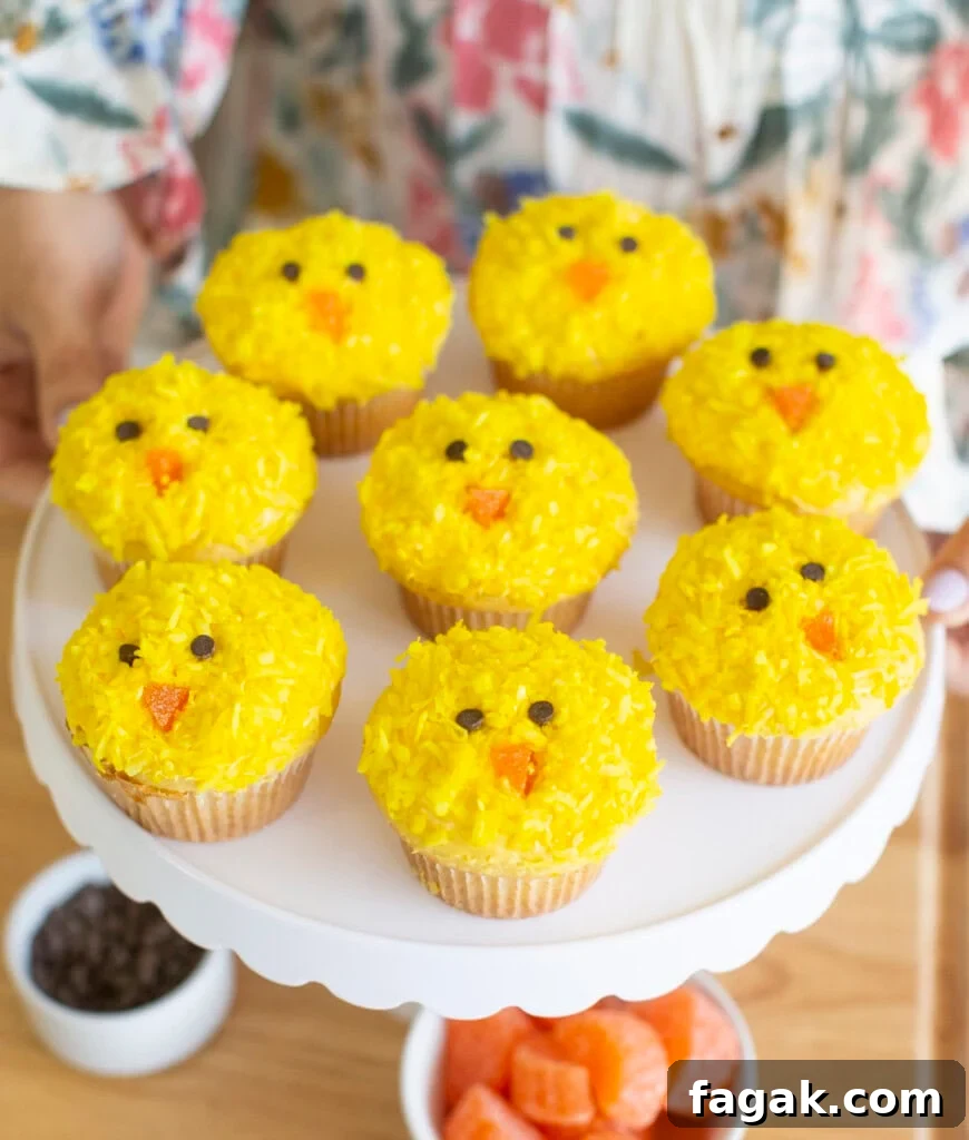 Yellow Easter chick cupcakes on a white cake stand.
