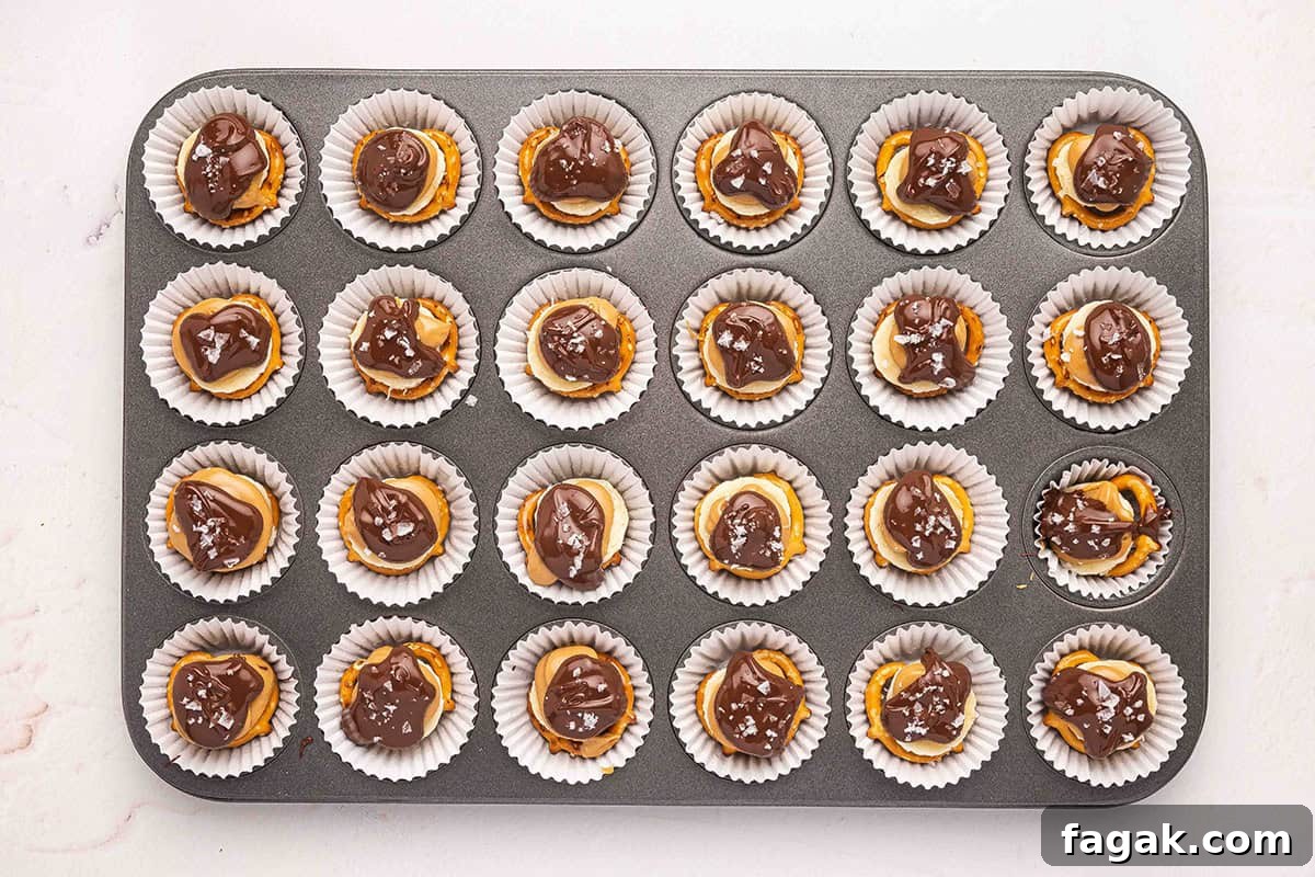 Peanut butter chocolate banana pretzel bites in a lined muffin pan, topped with flaky salt.