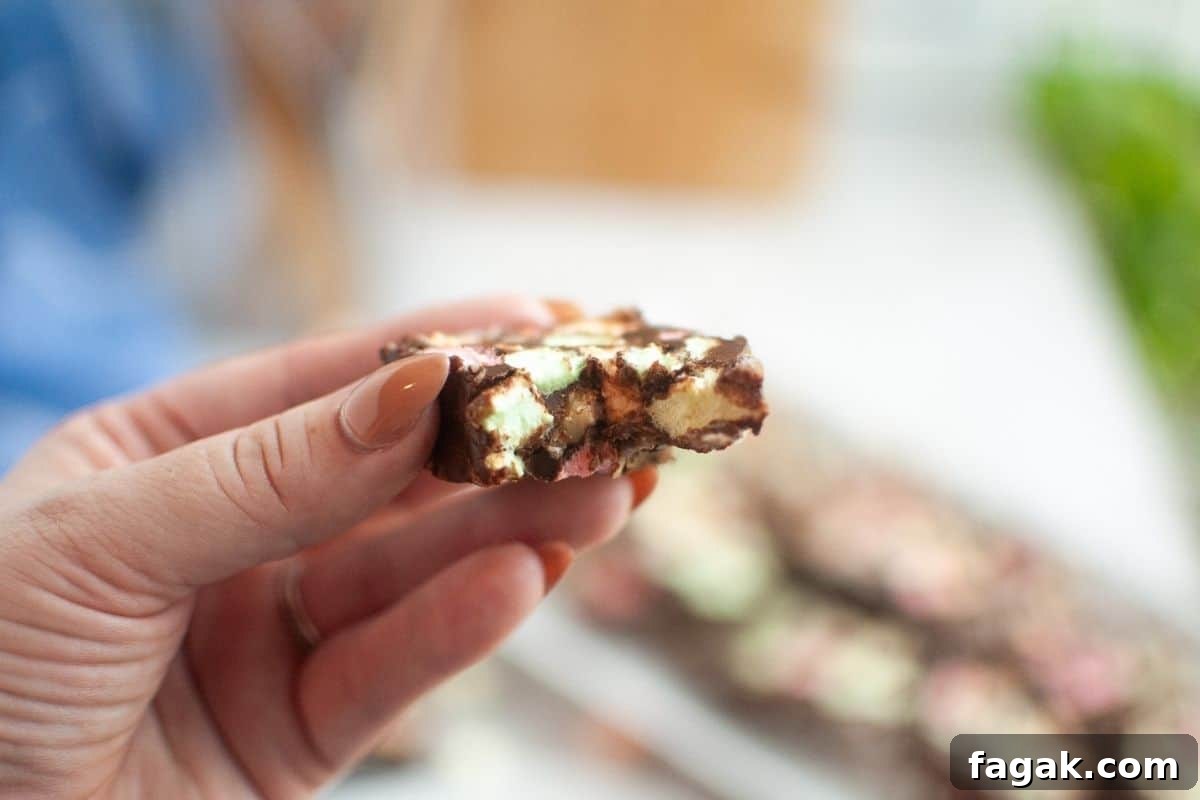 A hand holding a piece of Church Window Cookies, with more pieces blurred in the background.