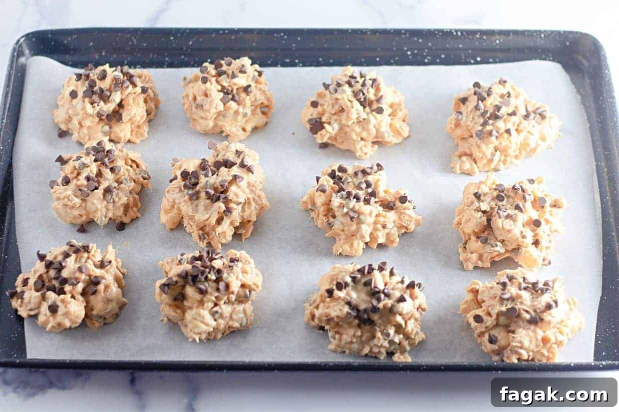 A baking tray lined with parchment paper holds twelve Avalanche Crunch Cookies.