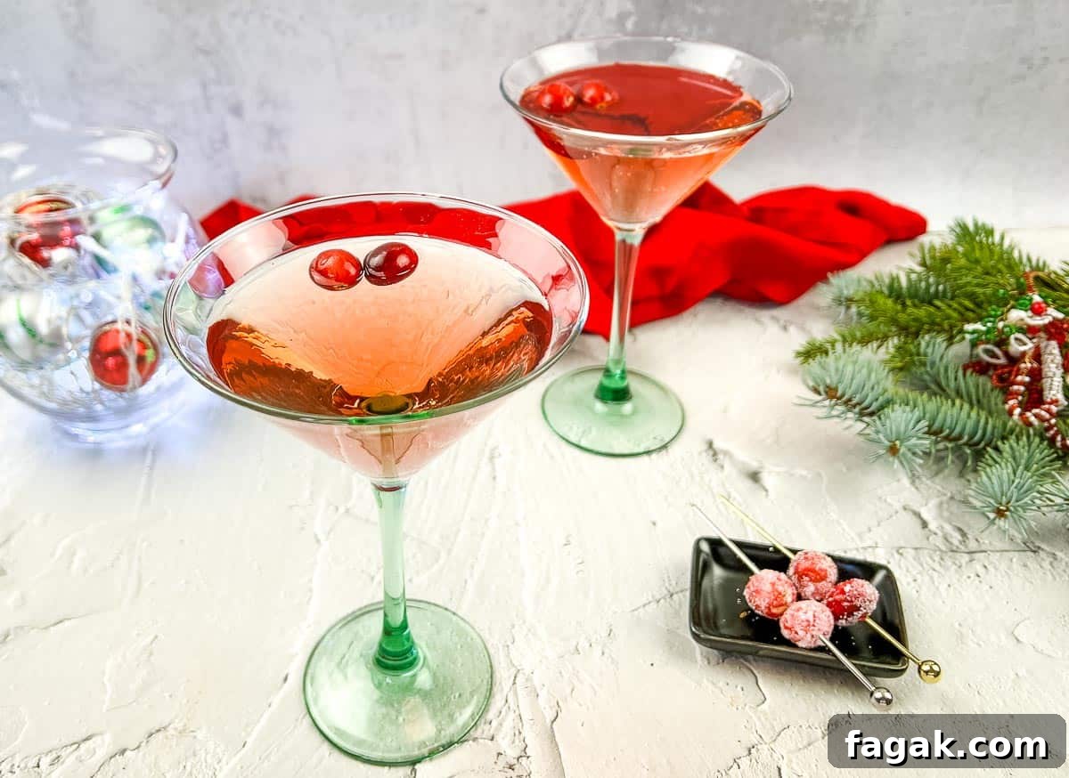 Two glasses of cranberry cosmosa and a christmas tree on a table.