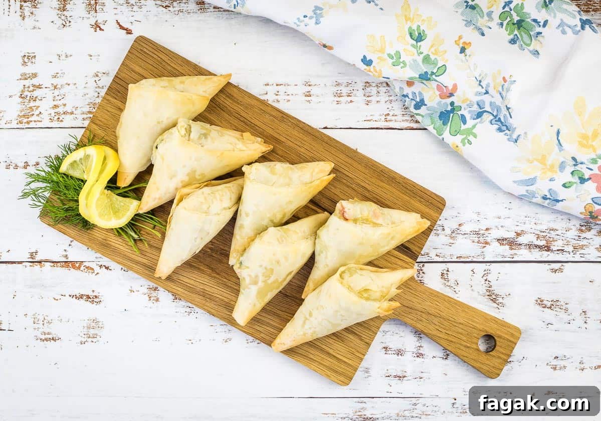Crab Spanakopita triangles on a cutting board.