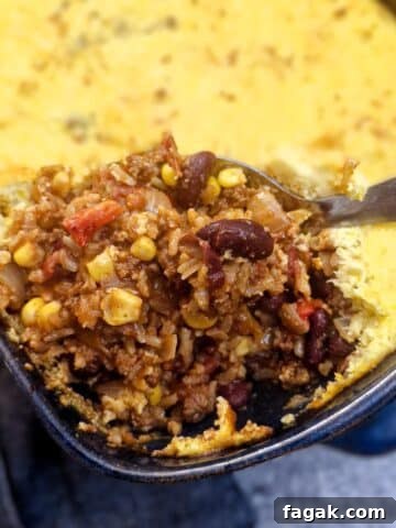 A spoon ful of chilli con carne corn casserole being lifted from a dish.
