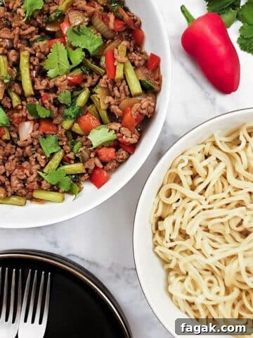 Overhead shot of a dish of Thai pork mince stir fry with a dish of noodles.