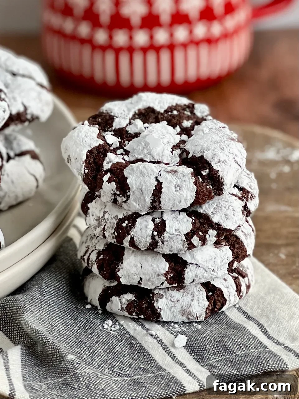 4 dark chocolate cookies with powdered sugar over them stacked on top of each other.