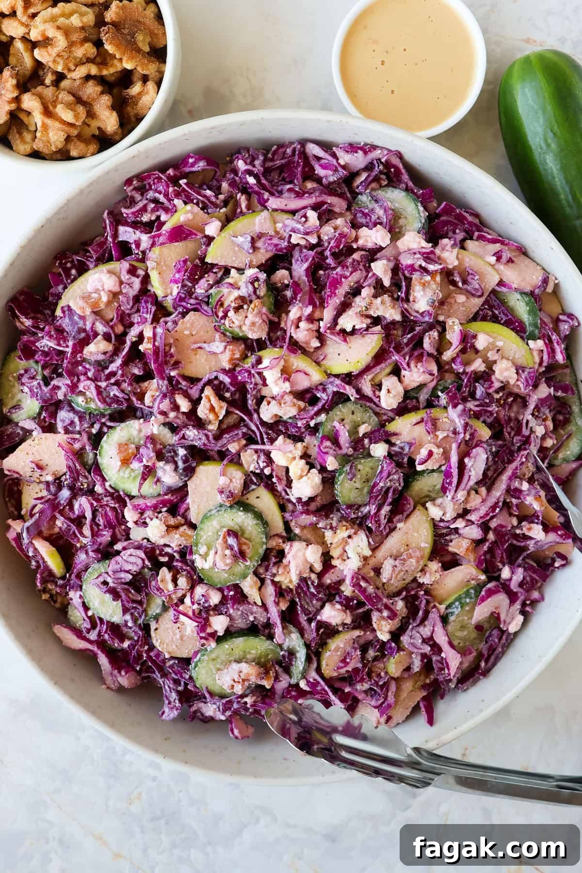 Red cabbage salad in a bowl with tongs.