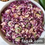 Red cabbage salad in a bowl with tongs.