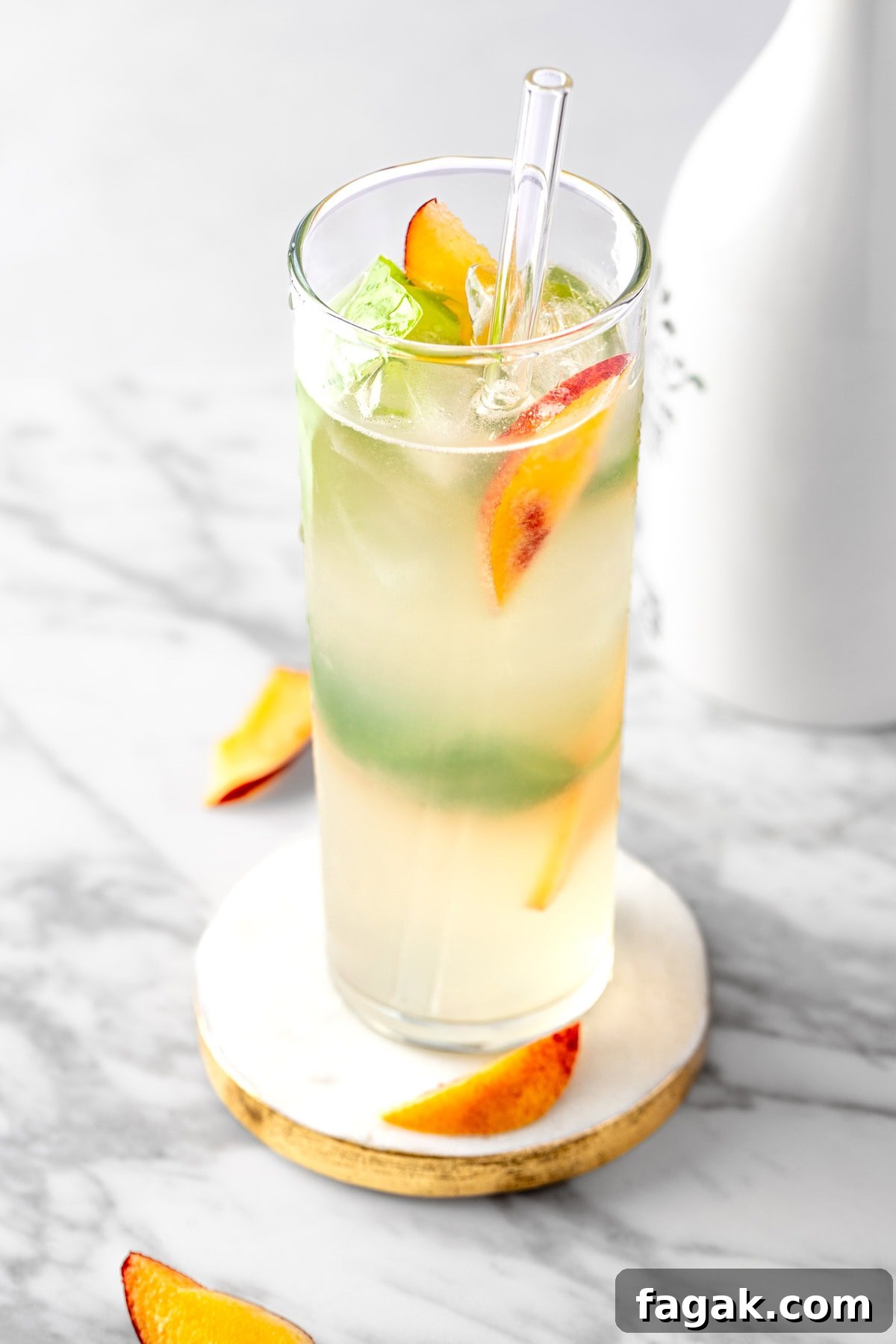 A peach basil mojito garnished with fresh basil leaves and peach slices.