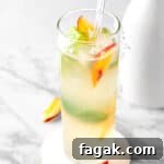 A peach basil mojito garnished with fresh basil leaves and peach slices.