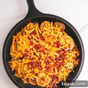Irish Pub Nachos Recipe: Swap Potatoes for Crispy Tortilla Chips 2 Flat lay photo of a skillet with baked potato slices topped with shredded sharp cheddar cheese and cooked chopped bacon