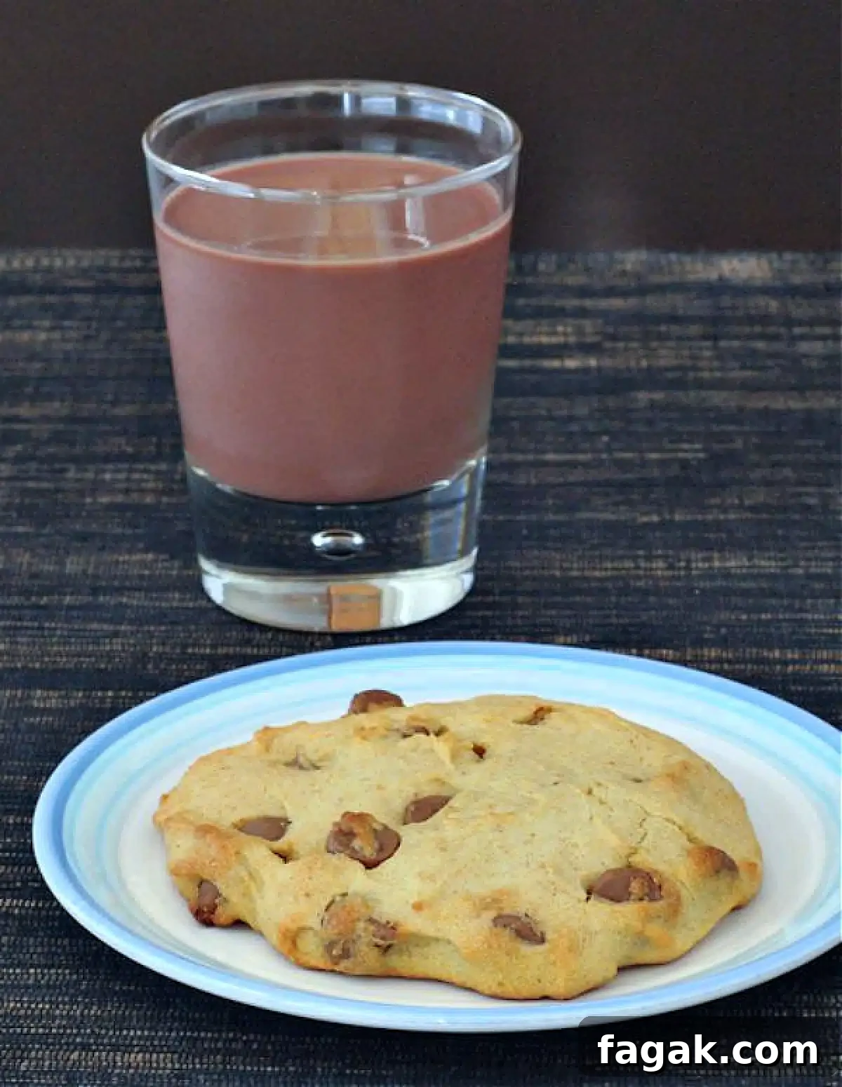 Single Serve Chocolate Chip Cookie @spabettie #glutenfree #vegan A single serve chocolate chip cookie on a white plate. A short glass of chocolate milk sits next to the plate.