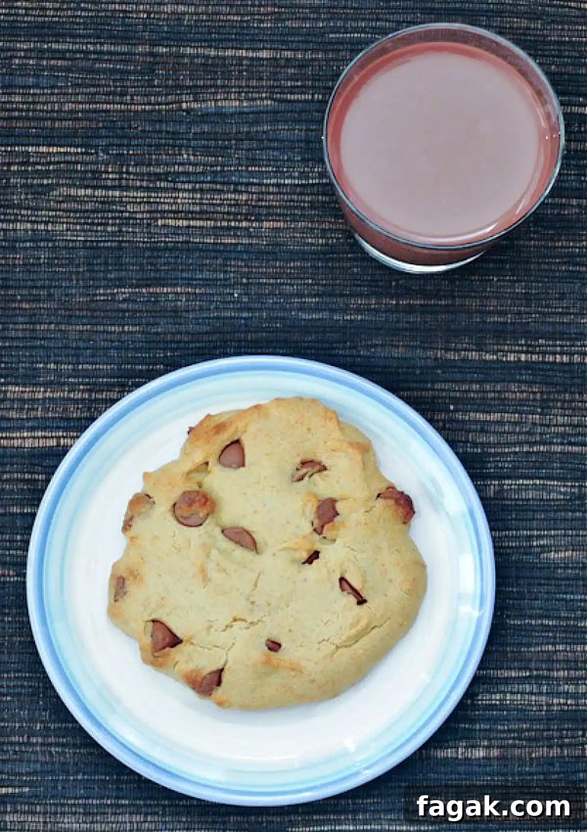 Single Serve Chocolate Chip Cookie @spabettie #glutenfree #vegan Overhead view of a single serve chocolate chip cookie on a white plate. A short glass of chocolate milk sits next to the plate.