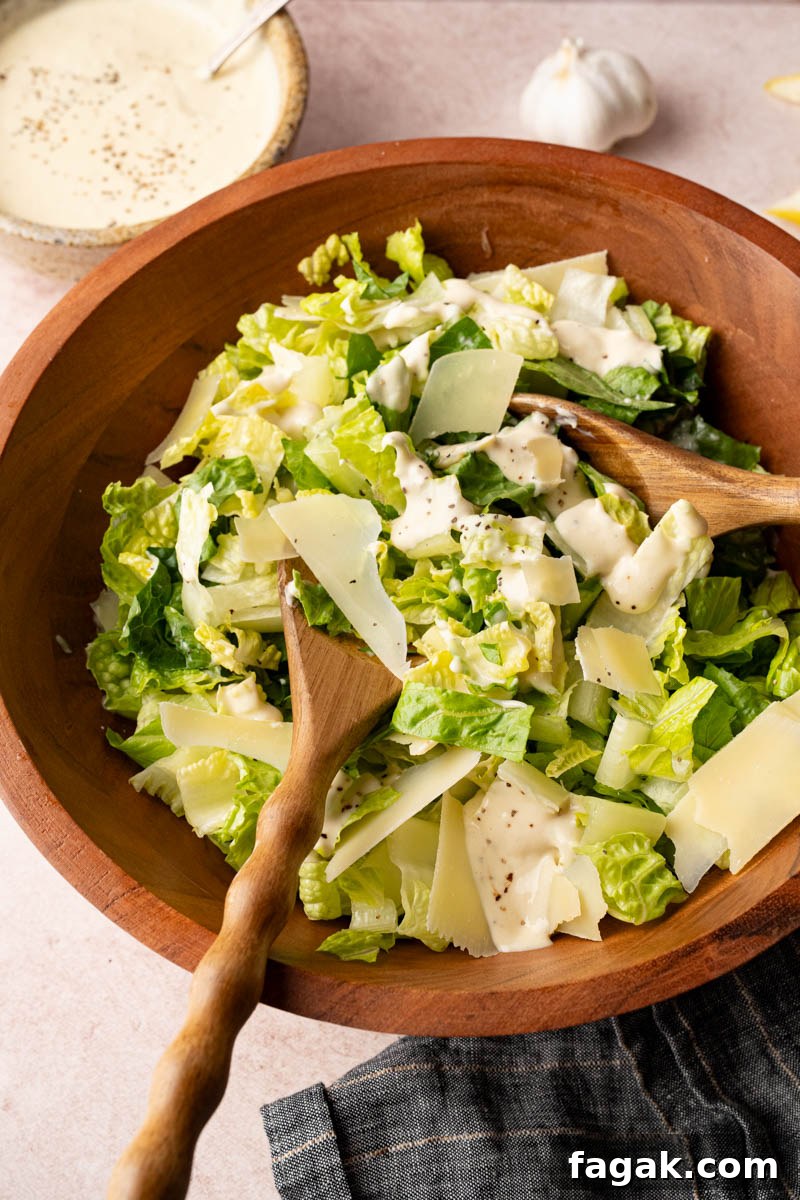 Tossing together the romaine lettuce, parmesan cheese and homemade caesar dressing in a wooden bowl before serving.