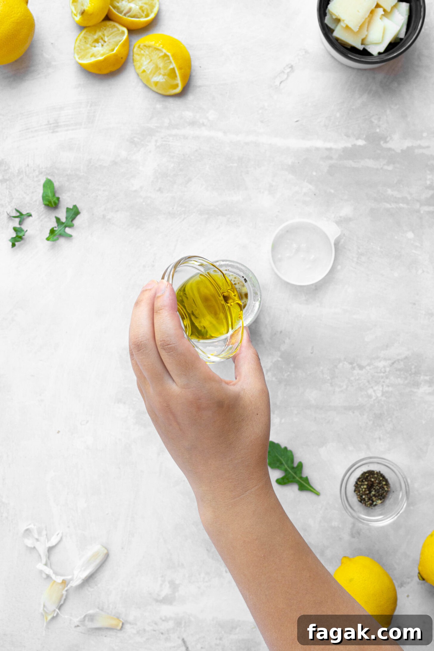 Citrus Arugula Salad with Lemon Vinaigrette 4 A hand pouring olive oil into a glass jar.