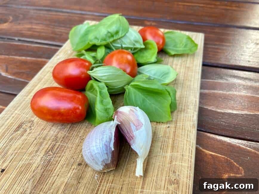 Fresh Tomato, Basil & Mozzarella Pasta Recipe for Summer 5 Tomatoes, fresh basil, and garlic cloves on a small wooden cutting board.