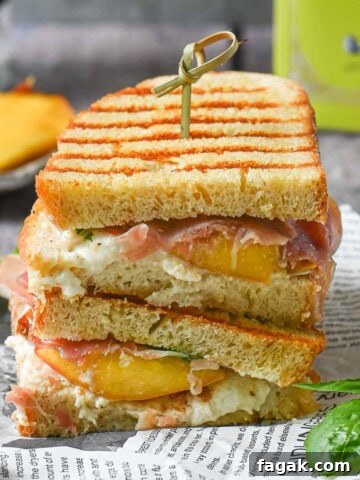 Peach panini stacked on deli paper with basil and peaches in the background.