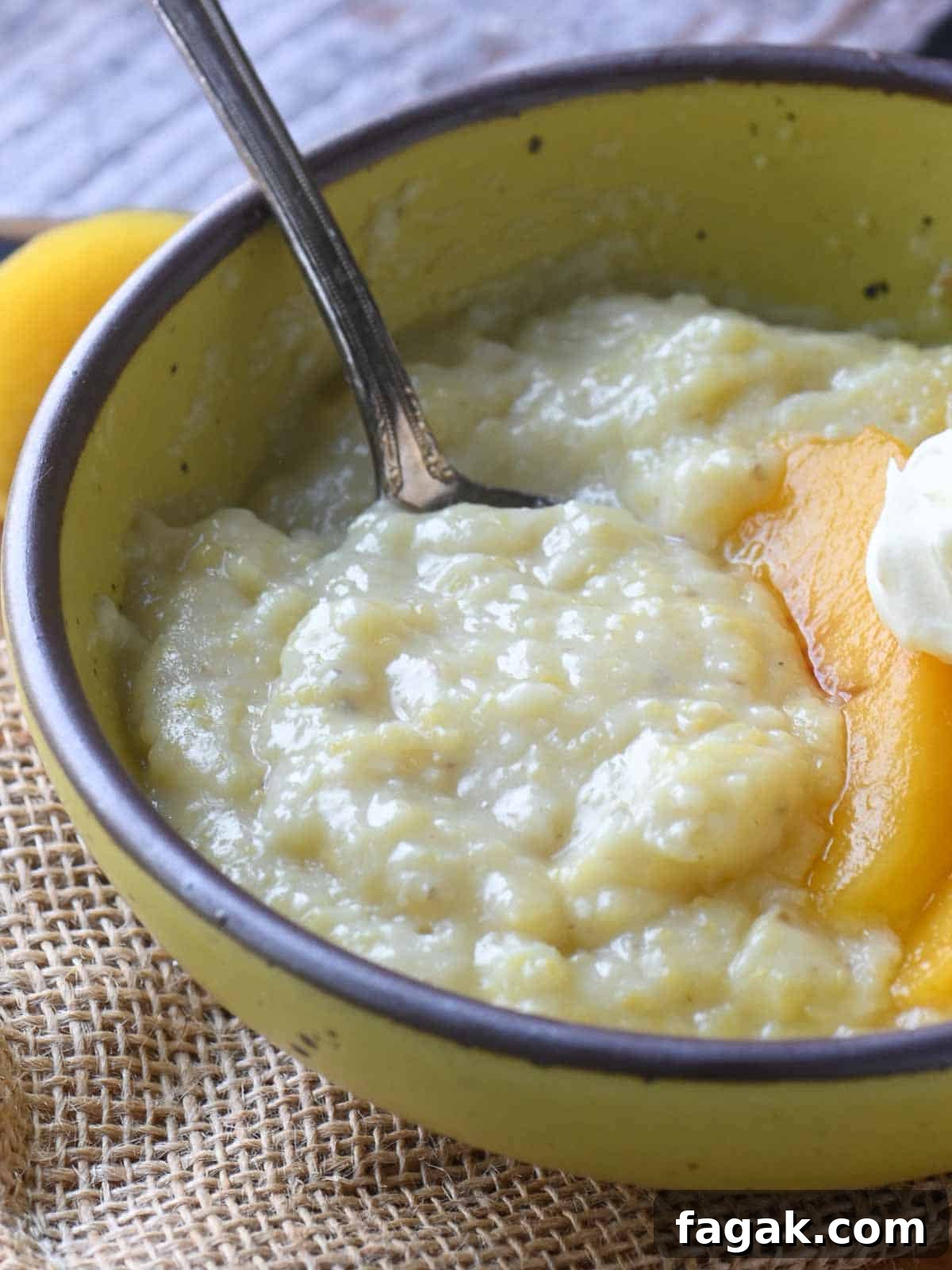 An angled view of creamy polenta in a yellow bowl with a spoon.