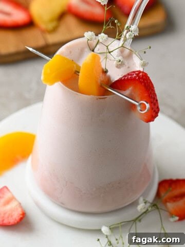 Angled view of a strawberry peach smoothie in a clear glass.