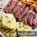 close up shot of corned beef & cabbage with potatoes, carrots, and onion on a white platter