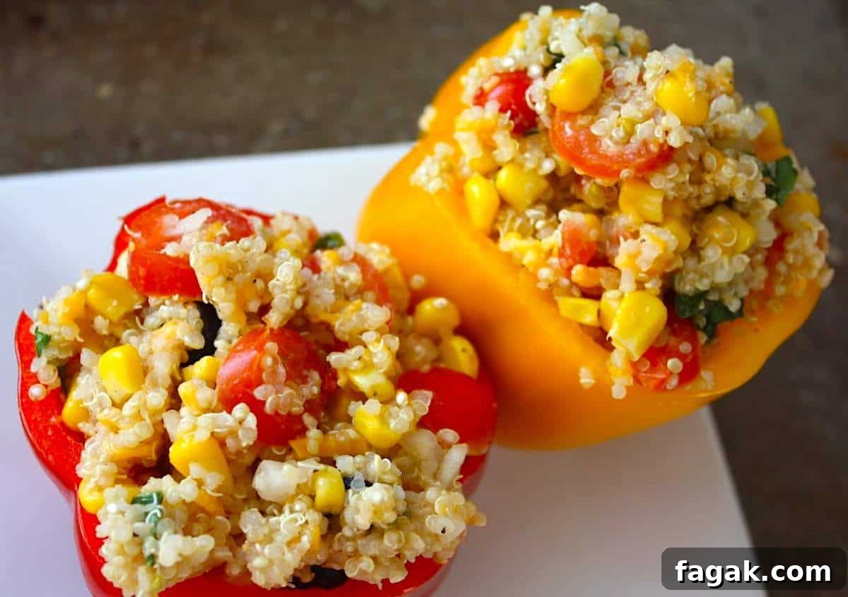 Two quinoa stuffed bell peppers on a white plate.