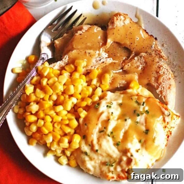 A plate of juicy slow cooker turkey breast smothered in gravy with mashed potatoes and corn.