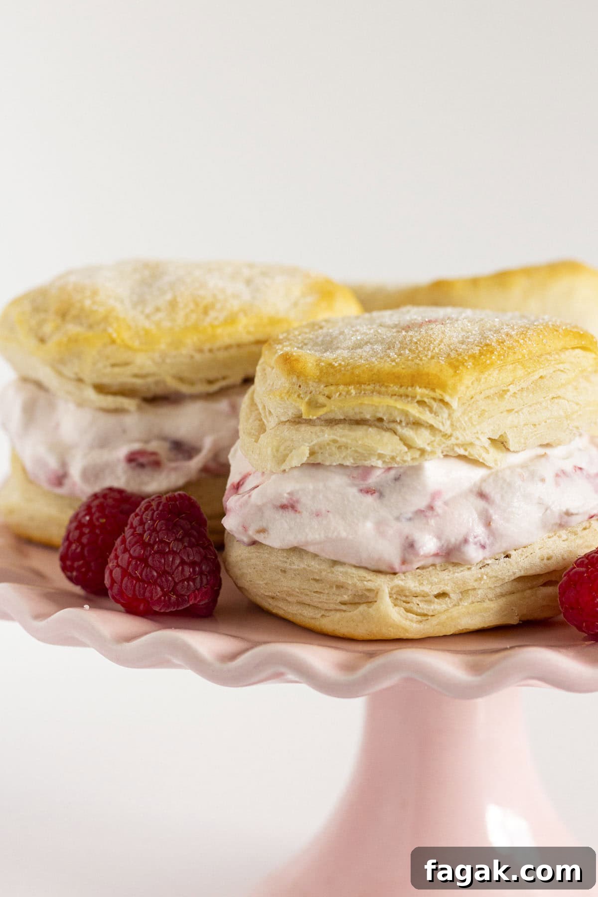 Raspberry shortcake on a pink cake plate with fresh raspberries.