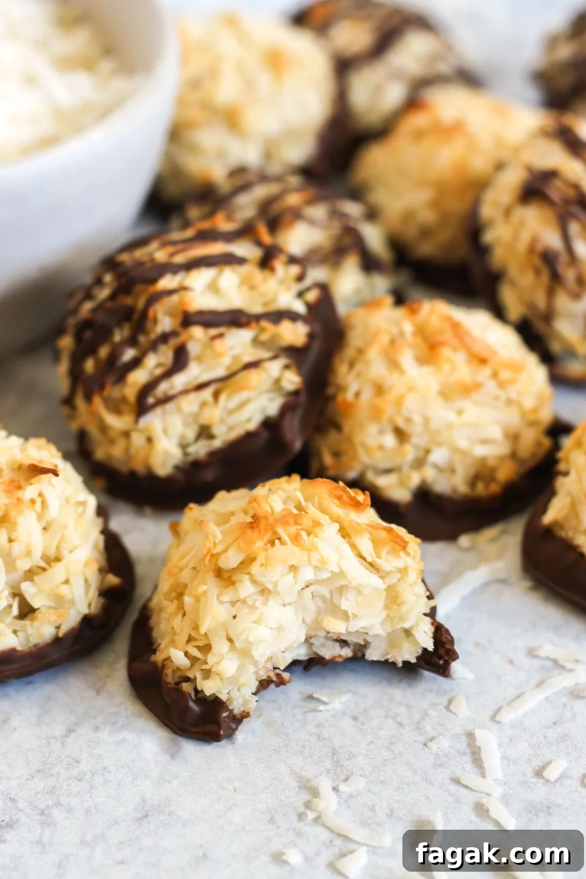 Coconut macaroon cookie with a bite taken out of it, with additional macaroons in the background.