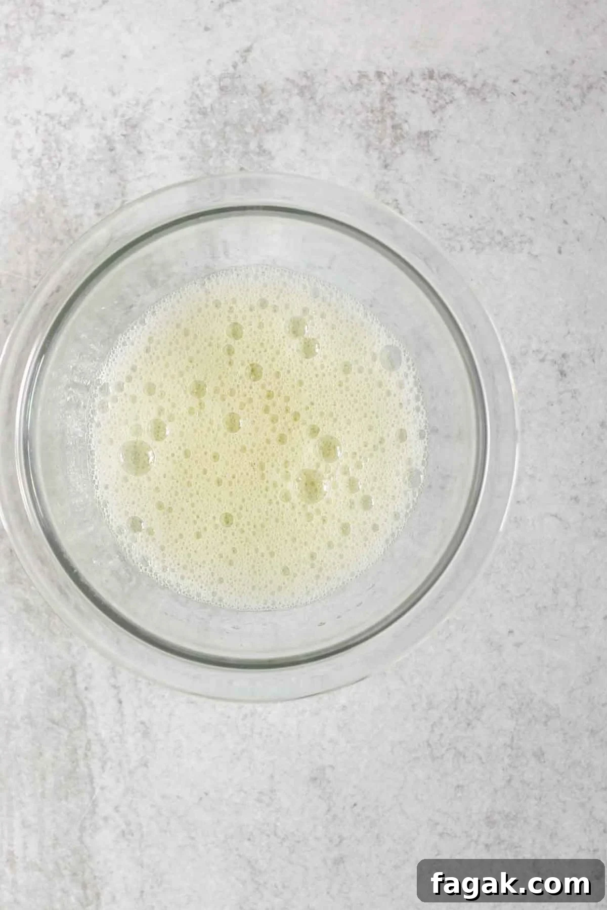 Whisked egg whites in a small glass mixing bowl.