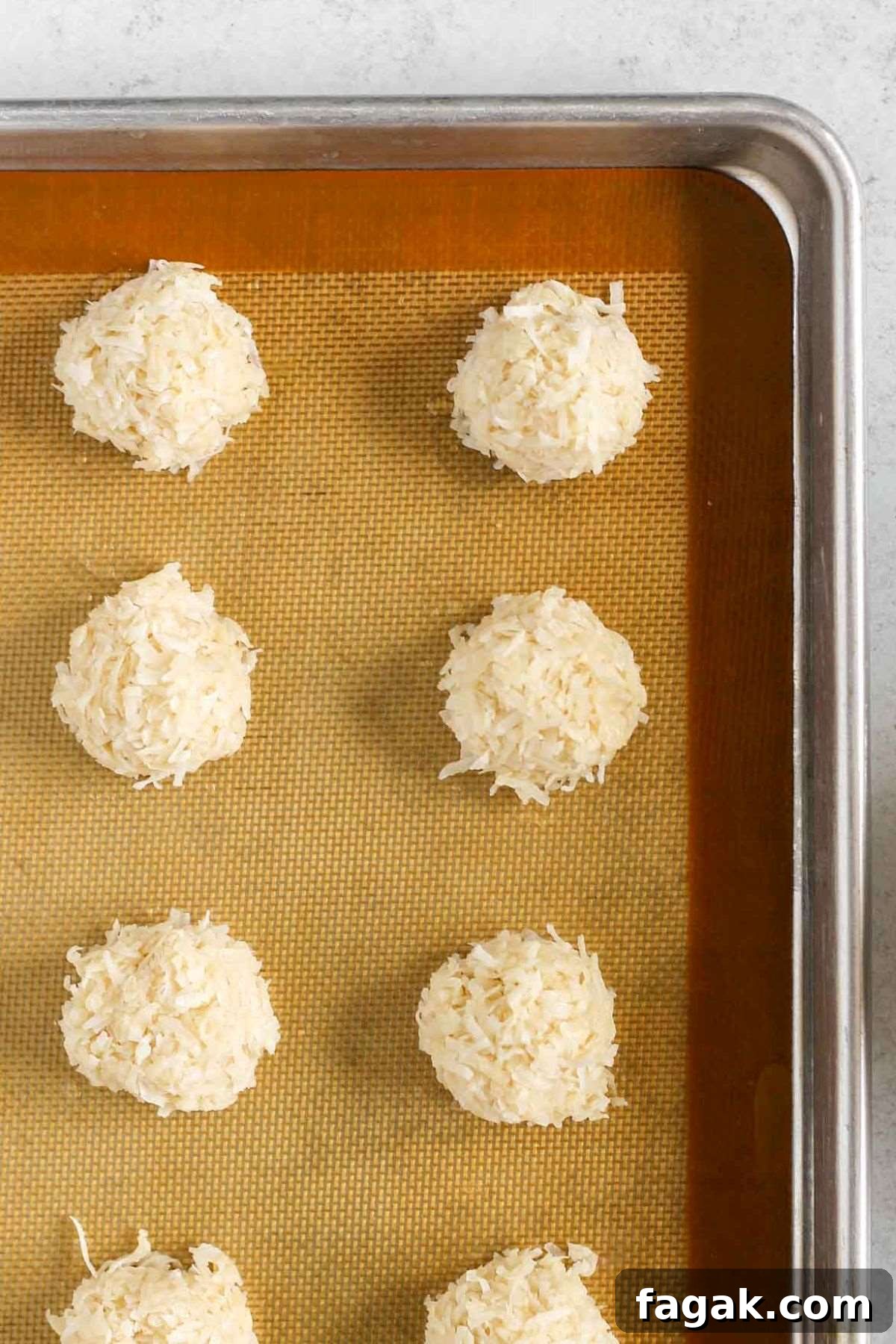 Raw coconut balls on baking sheet before baking.