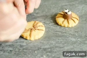 Drawing legs on biscuit for Cute Spider Halloween Biscuits on marble worktop
