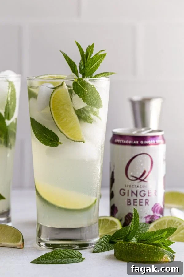 mojito with a can of Q ginger beer next to it. with lime wedges and mint all around
