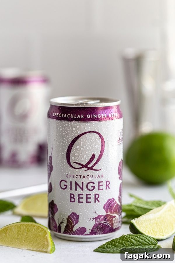 up close shot of a can of Q mixers ginger beer. with lime wedges and mint all around