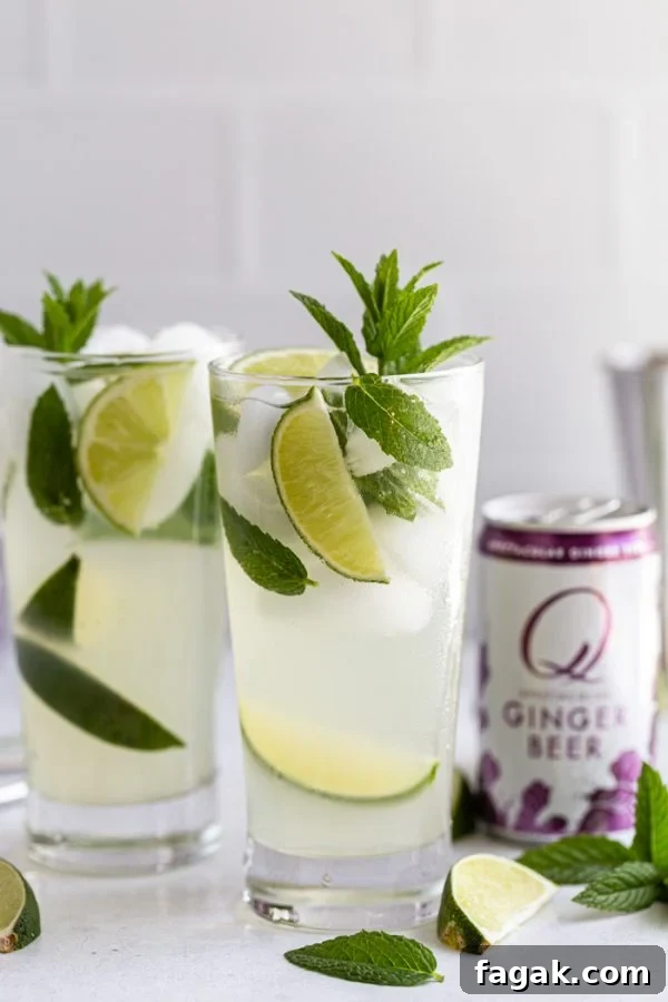 mojito with a can of Q ginger beer next to it. with lime wedges and mint all around
