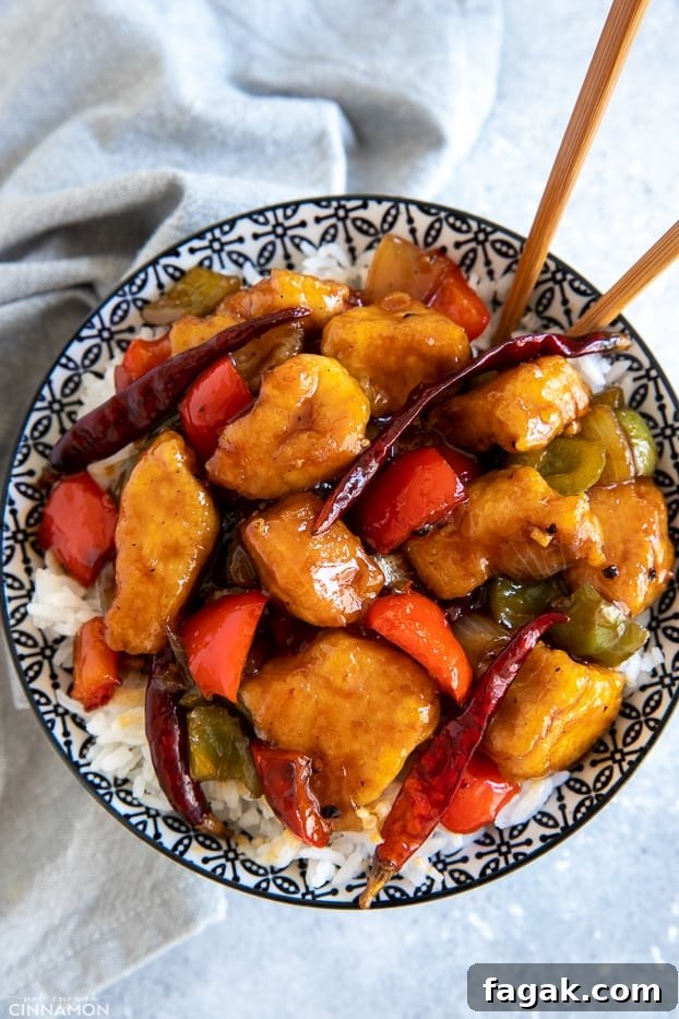 a bowl with Chinese Szechuan Chicken stir fry on rice with chopsticks 