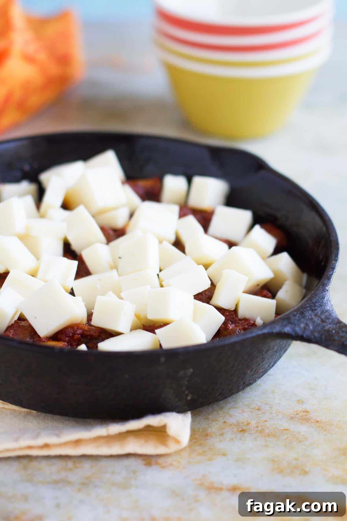 Cubes of cheese on top of chorizo and mushrooms.