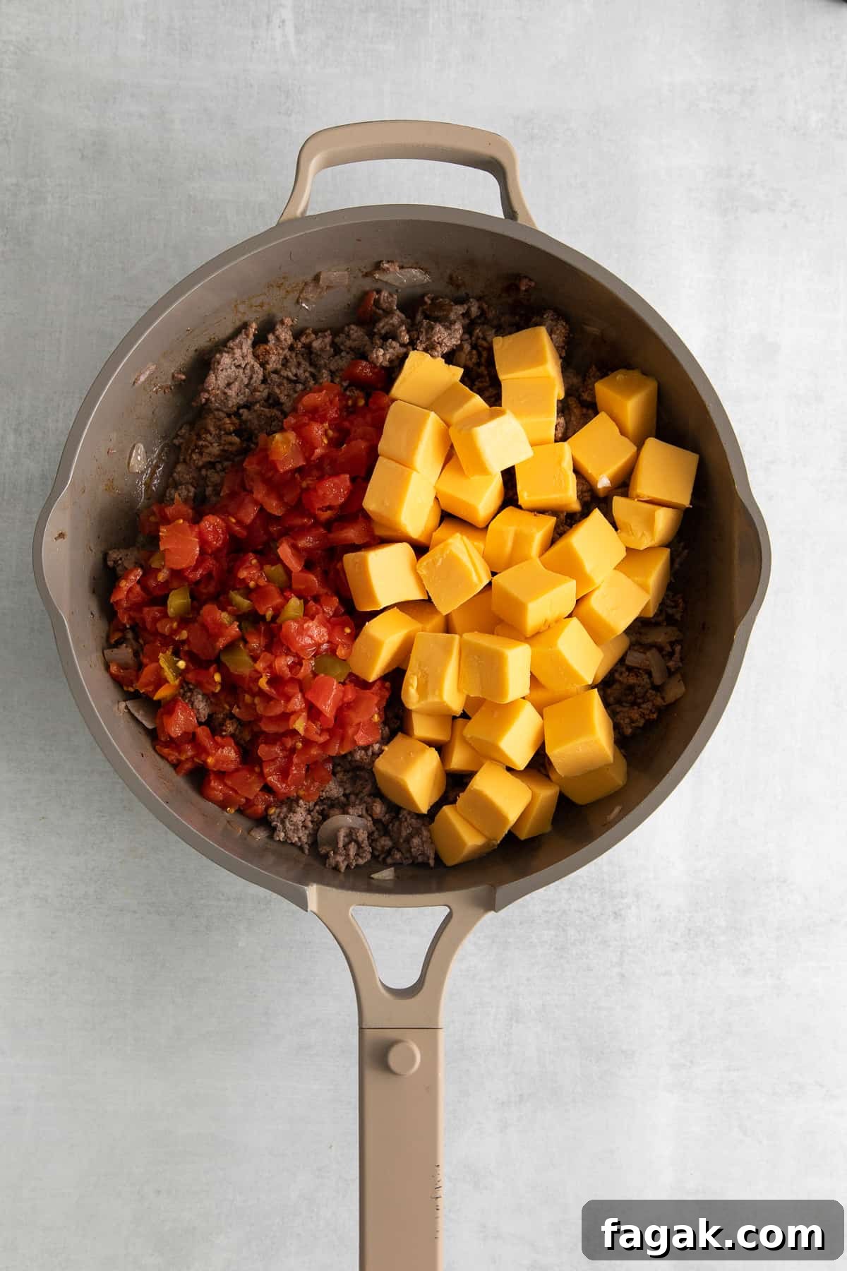 Ground beef and velveeta cheese in a skillet.