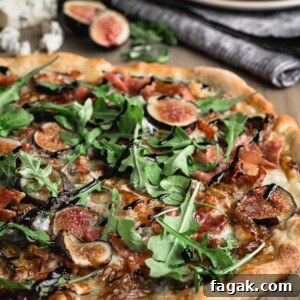 side view of a baked fresh fig pizza topped with baby arugula and a balsamic drizzle