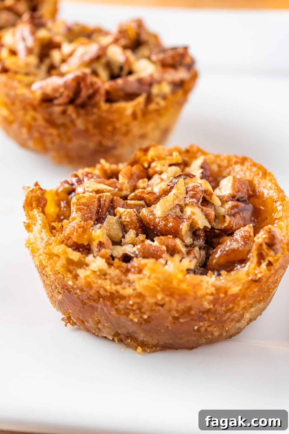 mini pecan pie tarts with a golden sugar cookie crust on a white plate. 