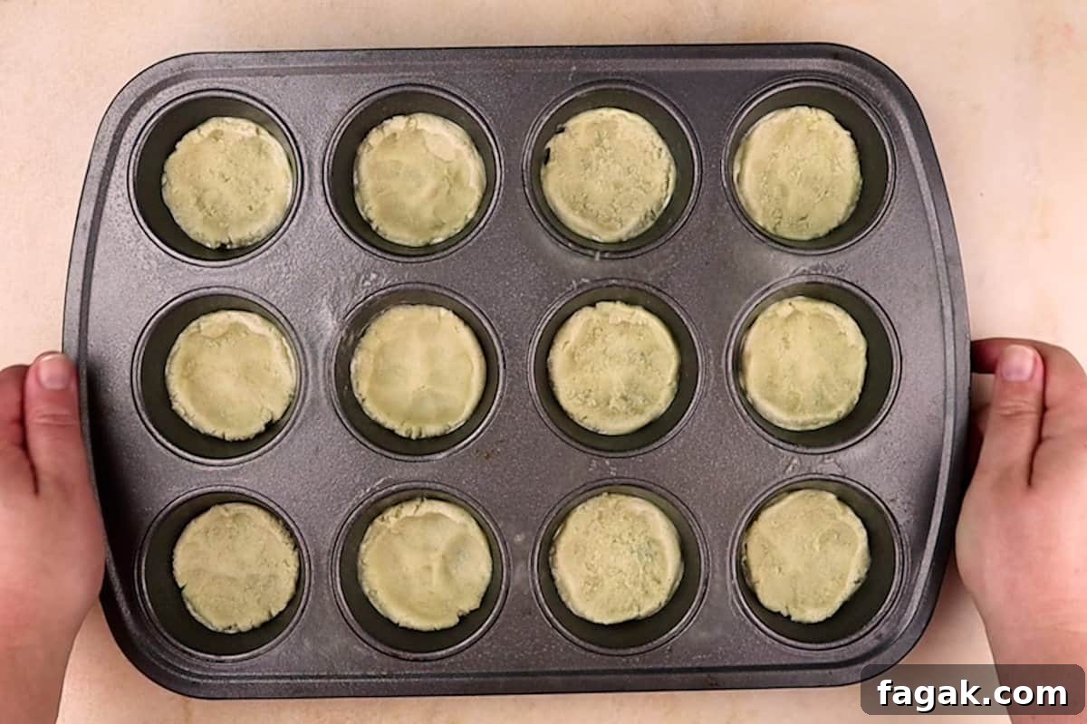 cookie dough pressed into a cupcake tin before baking.