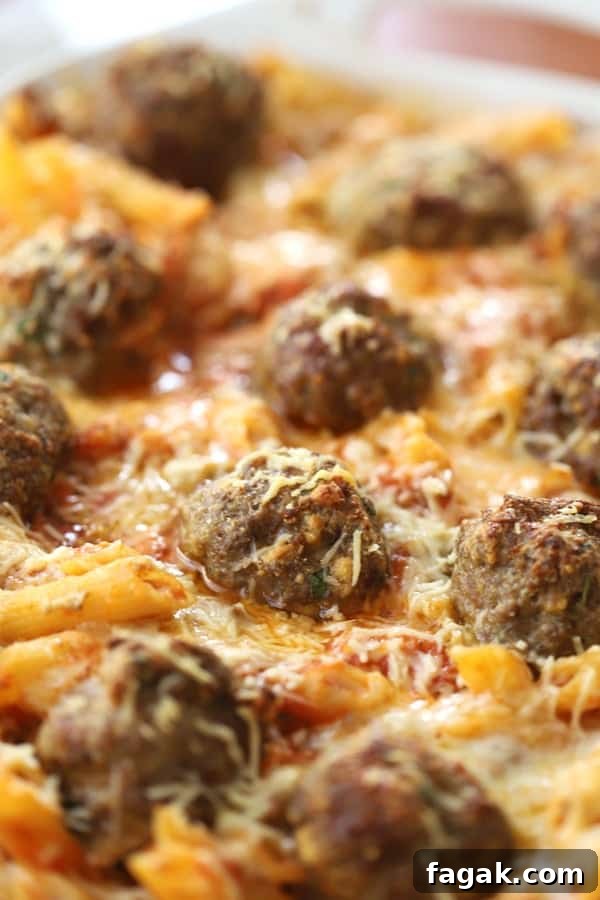 Baked penne pasta with meatballs in a baking dish.