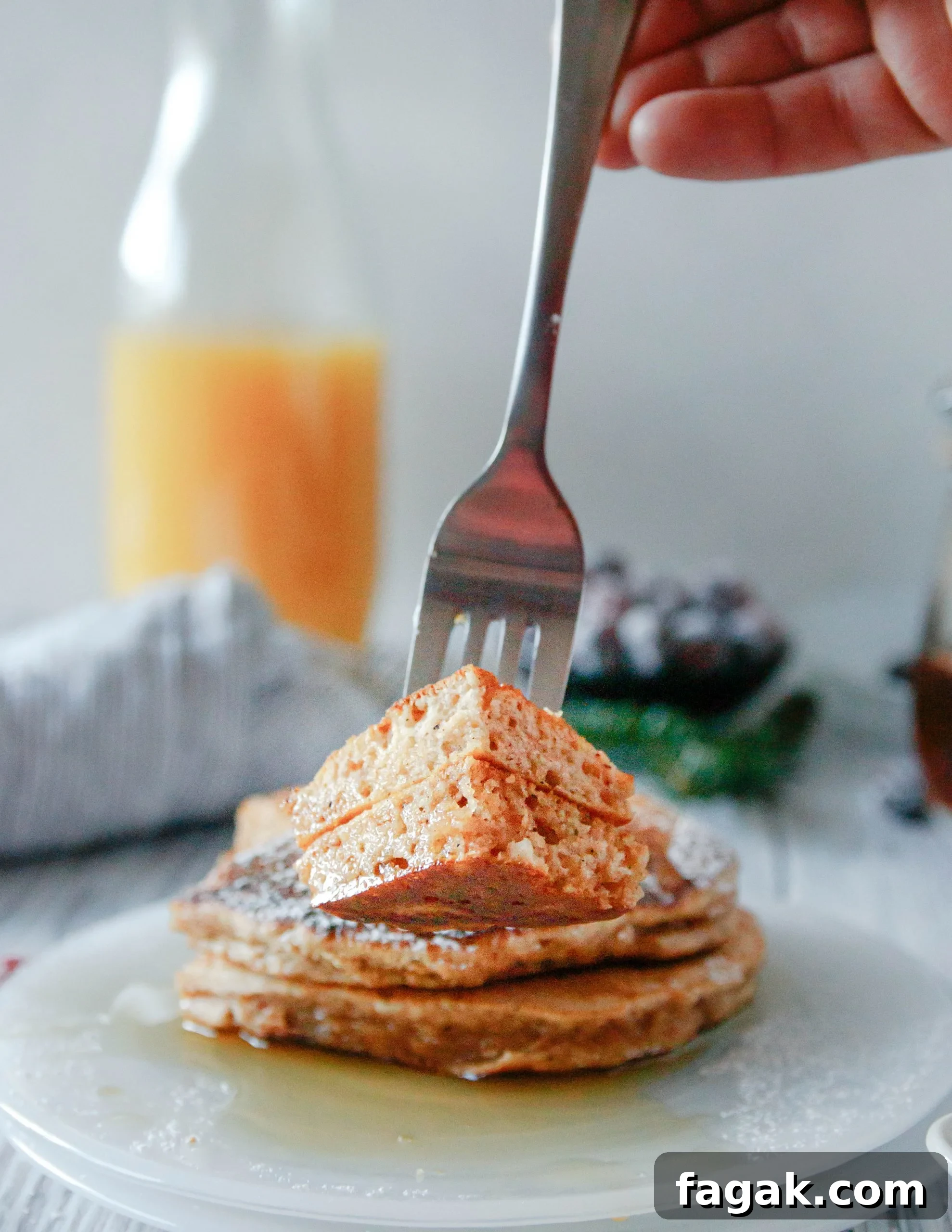 Close up of a cut portion of pancake on a fork to highlight the fluffy texture